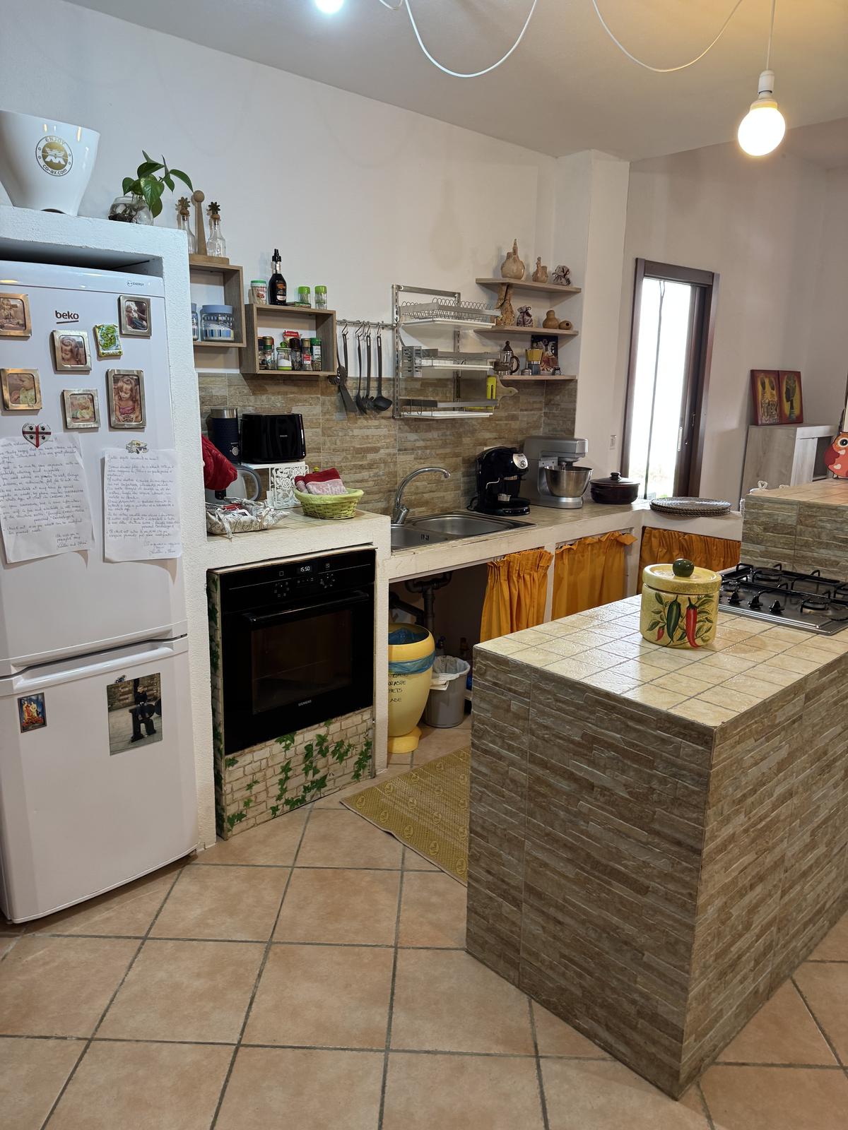 Cucina attrezzata con forno, piano cottura a gas, frigorifero e penisola piastrellata
