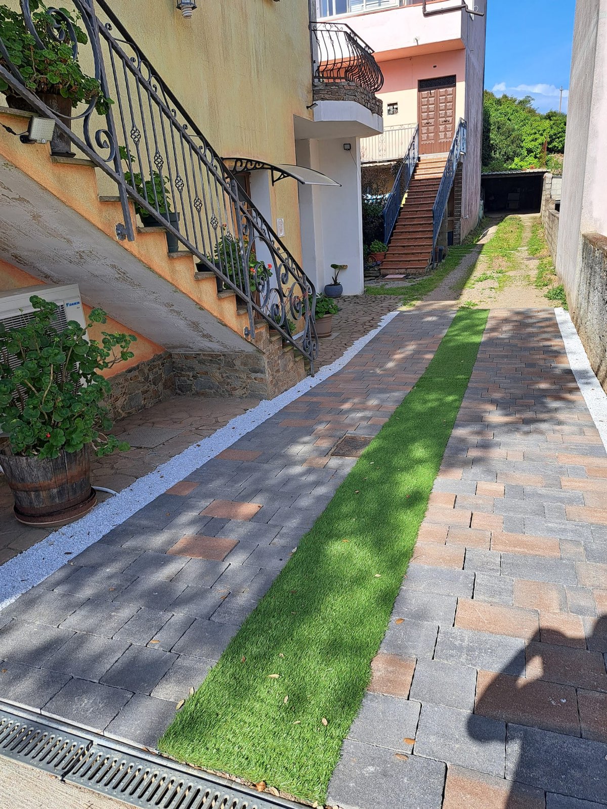 Vialetto pavimentato con fioriere di gerani