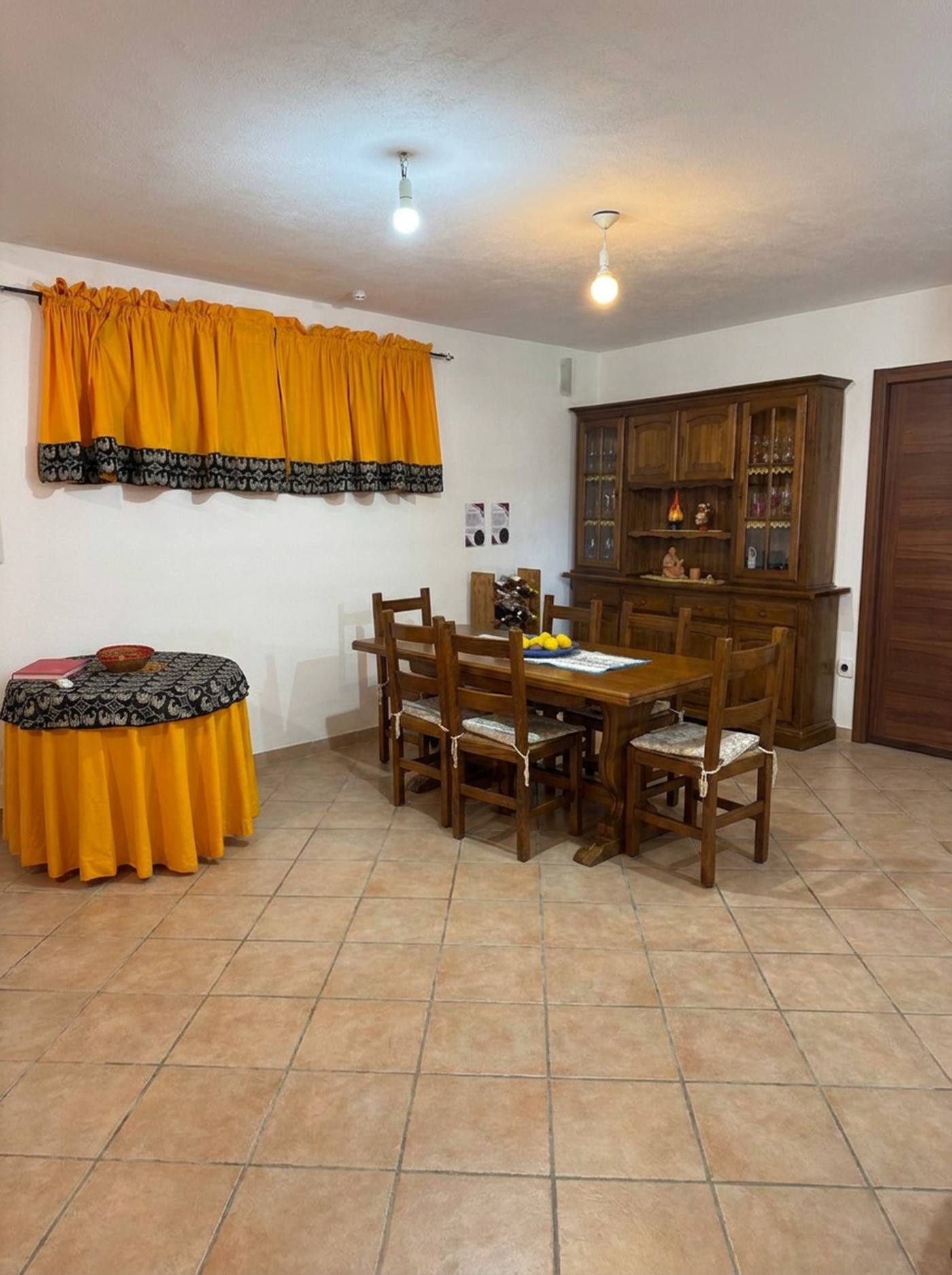 Zona pranzo con tavolo in legno, sei sedie e credenza